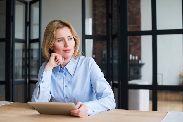 Thoughtful business woman using tablet at table