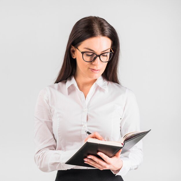 Thoughtful business woman writing in notebook with pen 