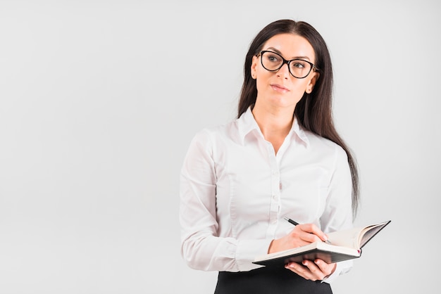 Thoughtful business woman writing in notebook 