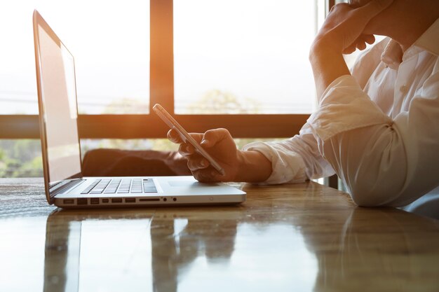 Thoughtful businessman or experienced entrepreneur using smartphone and laptop for analize information &#xD;