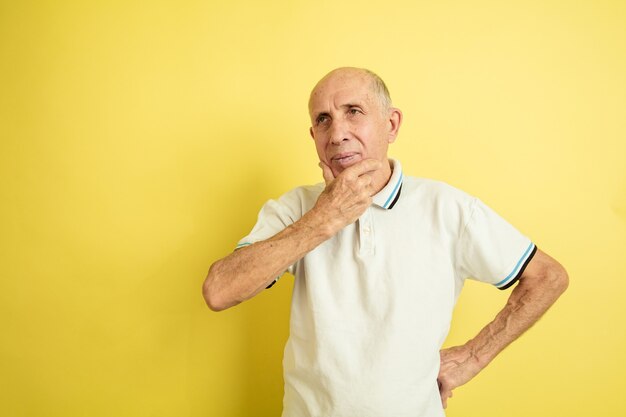 Вдумчивый. Портрет кавказского старшего человека, изолированные на желтом фоне студии. Красивая мужская эмоциональная модель. Понятие человеческих эмоций, выражения лица, продаж, благополучия, рекламы. Copyspace.