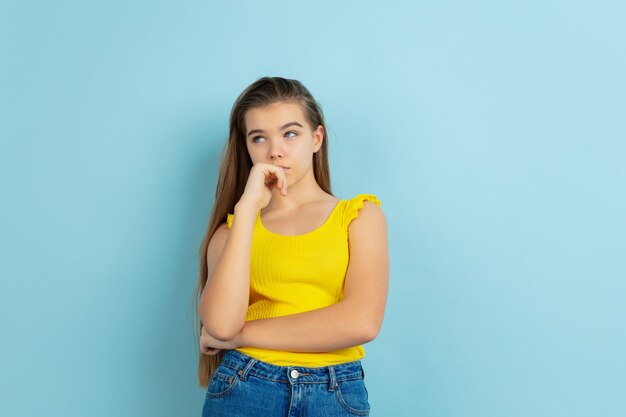 Thoughtful. Caucasian teen girl's portrait isolated on blue