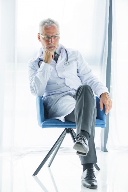 Free photo thoughtful doctor sitting on chair