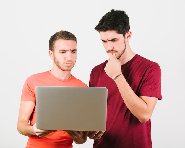 Thoughtful gay couple looking at notebook