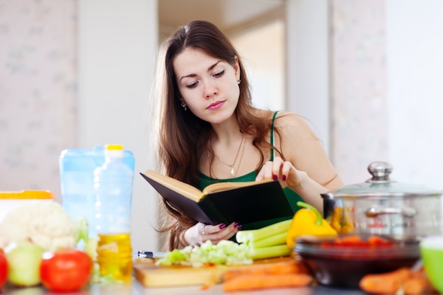 Вдумчивая девушка приготовления пищи с кулинарной книгой
