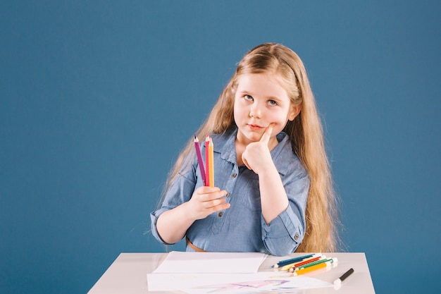 Thoughtful girl drawing at table