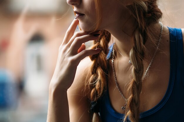 Thoughtful girl in a fitness suit poses before a window in a gym