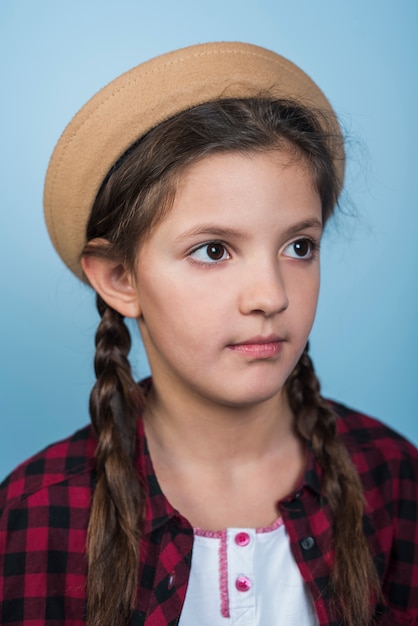 Thoughtful girl in hat with pigtails 