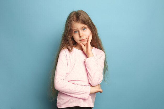 The thoughtful girl. The sad teen girl on a blue studio