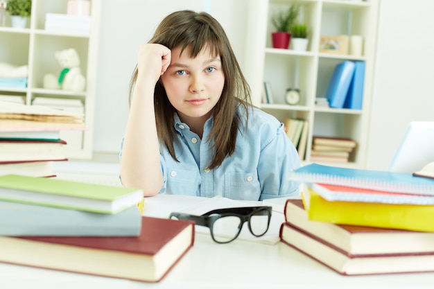 Free photo thoughtful girl surrounded by books