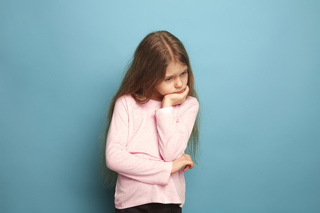 Foto gratuita la ragazza premurosa. ragazza teenager su un blu. le espressioni facciali e le emozioni delle persone concetto