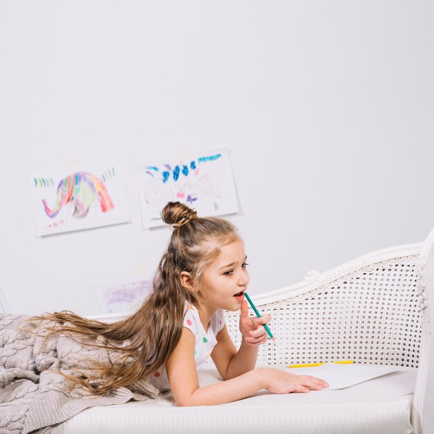 Thoughtful girl with pencil and paper on sofa