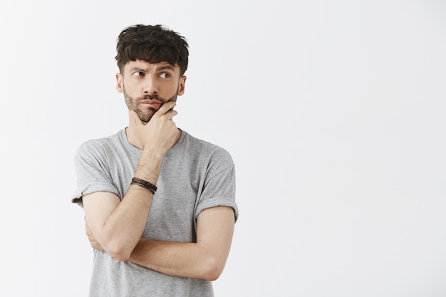 Free photo thoughtful handsome guy posing against the white wall