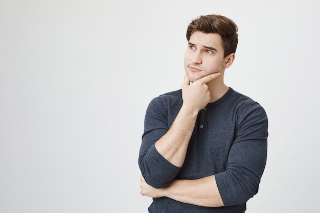 thoughtful handsome male student thinking, looking left pondering