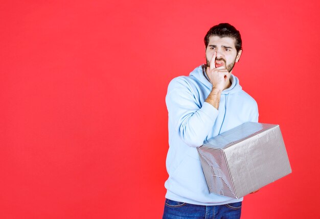 Thoughtful handsome man holding his gift box and looking away