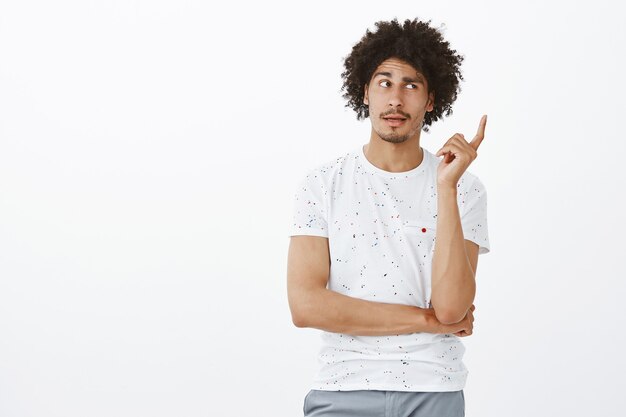 Thoughtful handsome man looking away while making assumption, thinking over white wall