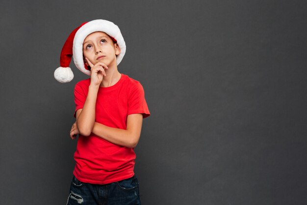 크리스마스 산타 모자를 쓰고 사려 깊은 작은 소년 아이