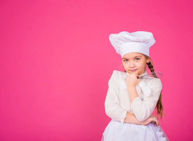 Thoughtful little girl cook with whisk 