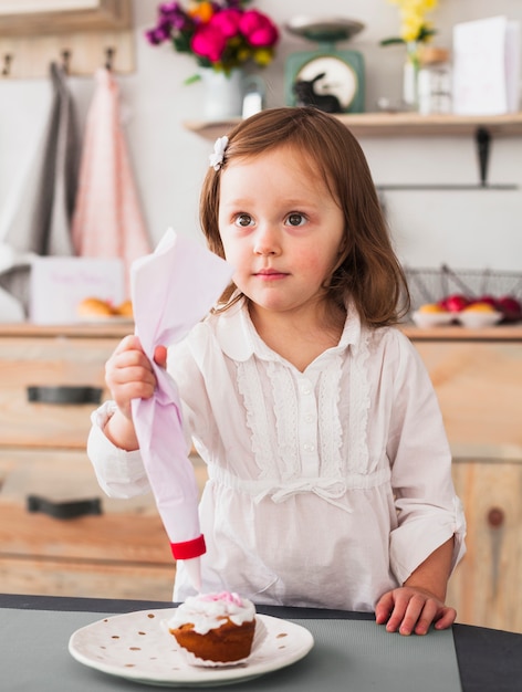 Thoughtful little girl making cupcake