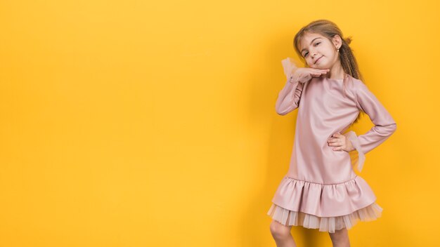 Thoughtful little girl posing on yellow background 