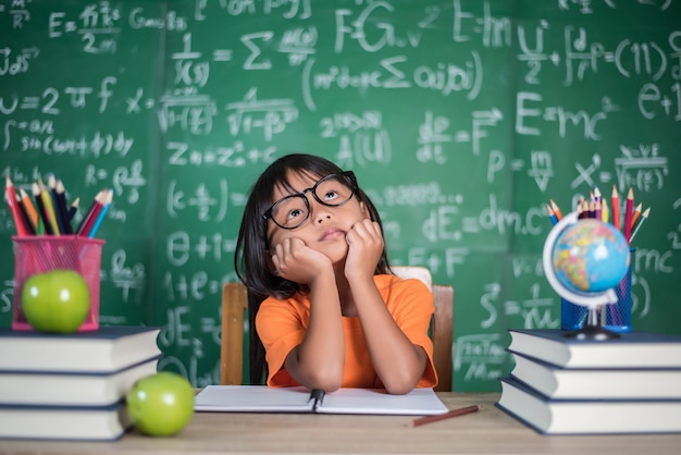 Thoughtful little girl with book near a school board