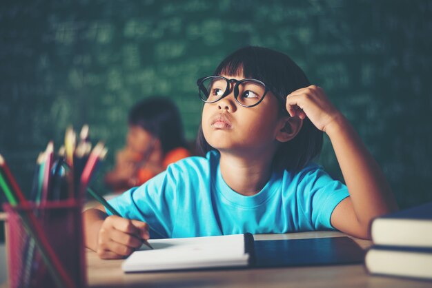 Thoughtful little girl with book near a school board