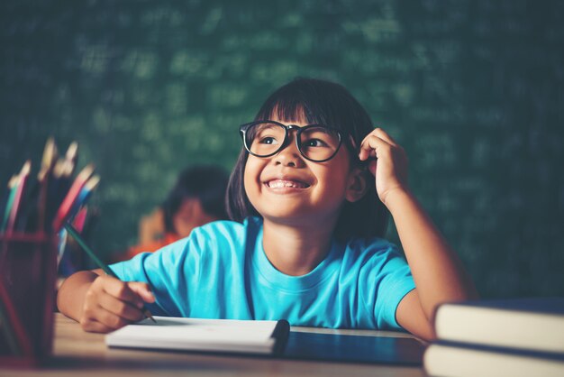 Thoughtful little girl with book near a school board