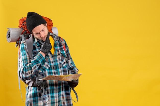 Free photo thoughtful male camper with leather gloves and backpack holding map