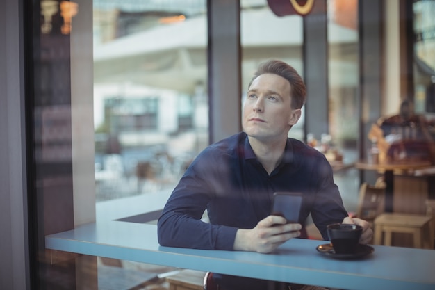 Thoughtful male executive holding mobile phone