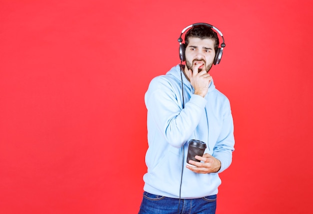 Uomo premuroso che tiene tazza di caffè e ascolta musica