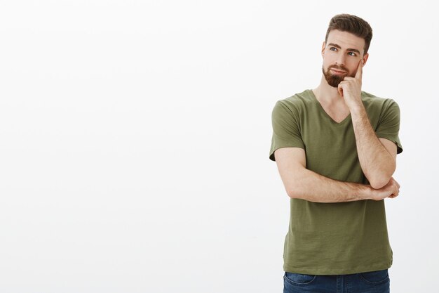 thoughtful man holding fist on cheek looking left at copyspace