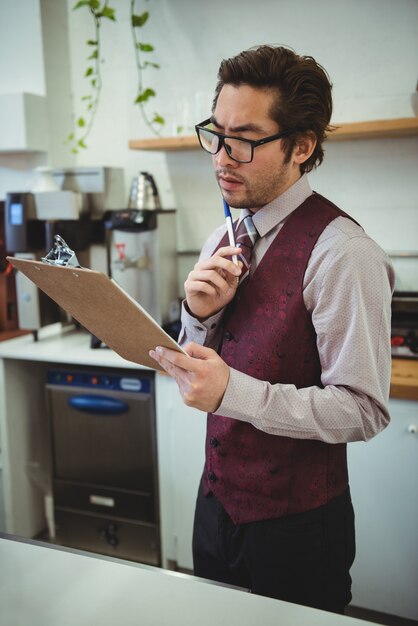 Thoughtful man looking at clipboard