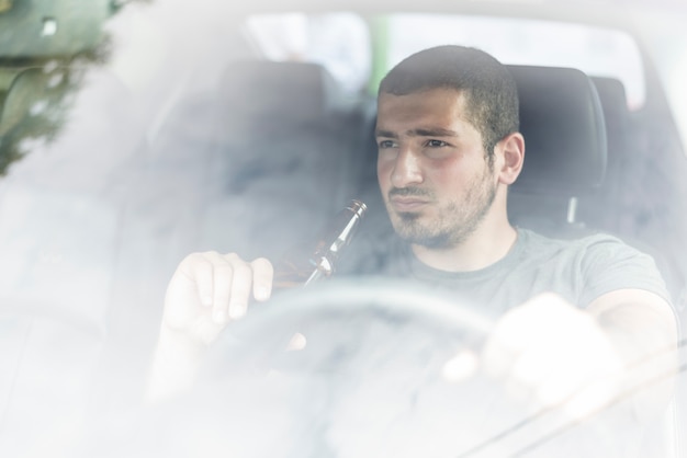 Thoughtful man with beer driving car