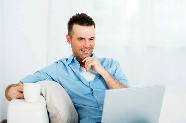 Thoughtful man with laptop and cup of coffee