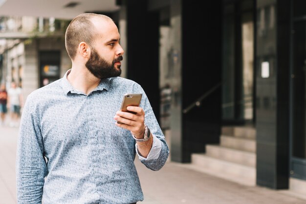 Thoughtful man with phone at street