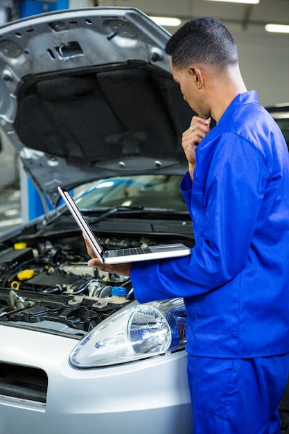 Thoughtful mechanic working on laptop