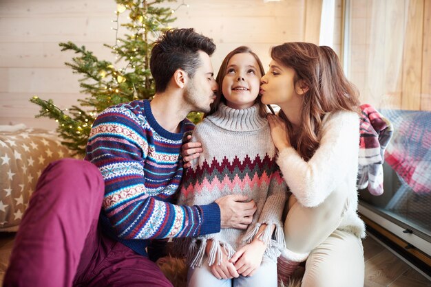 Thoughtful parents kissing their daughter