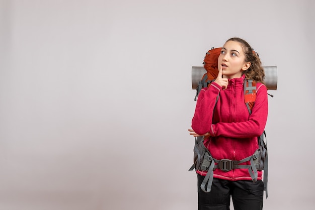 thoughtful pretty woman with big backpack standing on grey