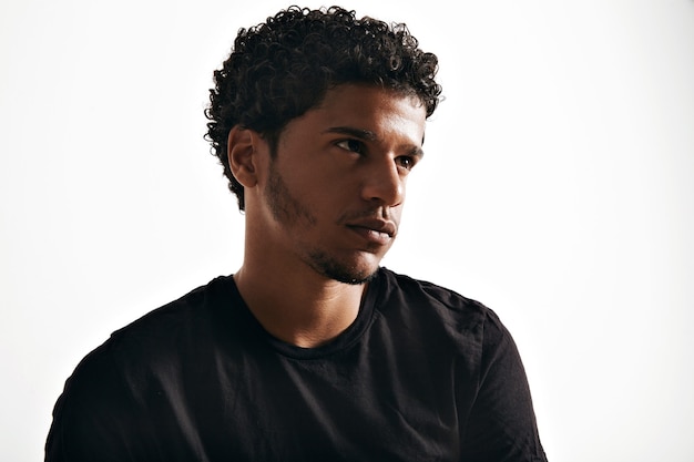 Thoughtful quiet young man wearing a blank black cotton t-shirt on white wall