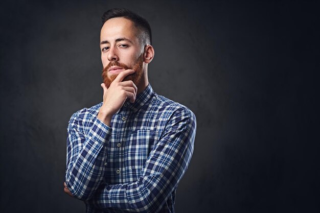 Thoughtful redhead bearded hipster male dressed in a blue fleece shirt.