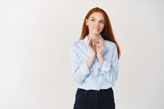 Thoughtful redhead girl smiling devious and steeple fingers like villain or evil genius, looking at upper left corner scheming something