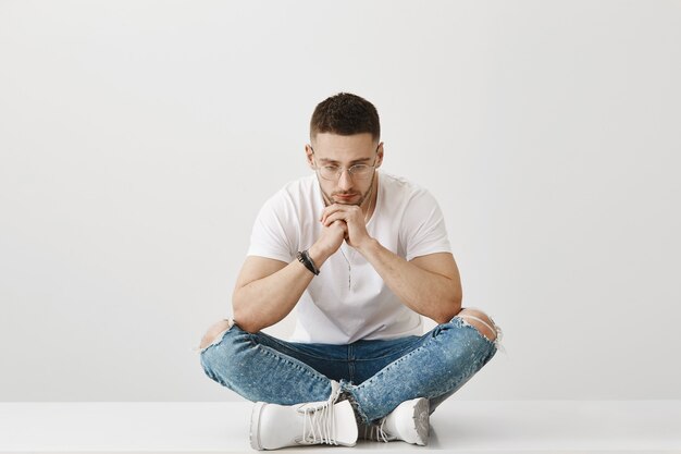 Thoughtful and sad young guy with glasses posing