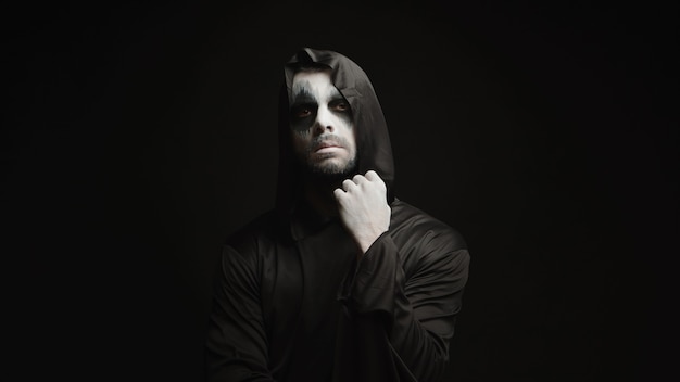 Free photo thoughtful scary grim reaper over black background. halloween demon.