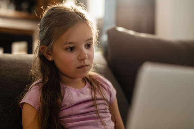 Thoughtful small girl surfing the net on a computer at home