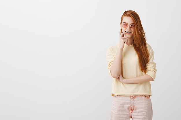 Thoughtful smiling redhead girl biting finger and looking left intrigued, have interesting idea