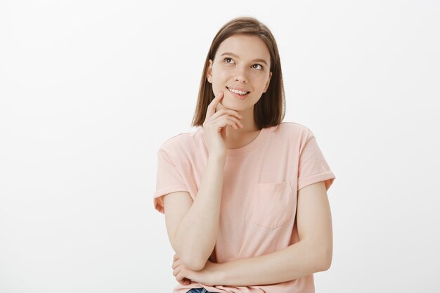 Thoughtful smiling woman looking upper left corner dreamy, tempted to try something