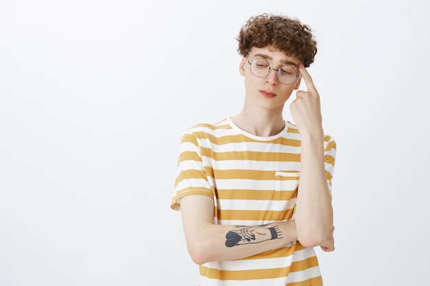 Thoughtful teenage guy posing against the white wall