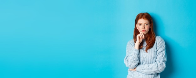 Thoughtful teenage redhead girl staring at camera pondering ideas making decision with serious face