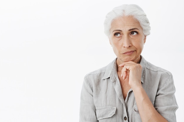 Thoughtful troubled old lady looking upper left corner, pondering