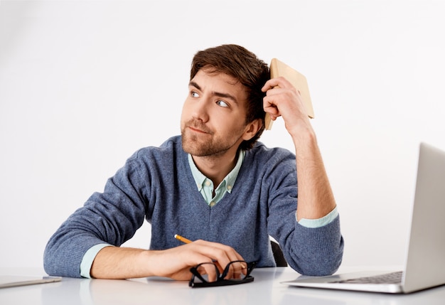 Thoughtful, troubled young office worker, lack ideas, look away with pouting serious face, trying think-up ideas for new story, hold planner and pencil